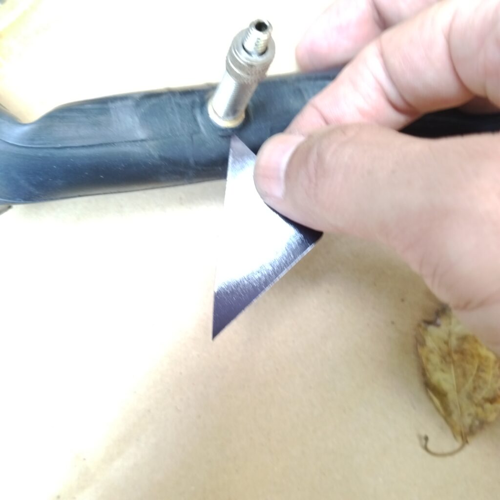 自転車のバルブ根元のパンクの修理で穴に接着剤を入れ込む水道広告マグネットをカットしたもの