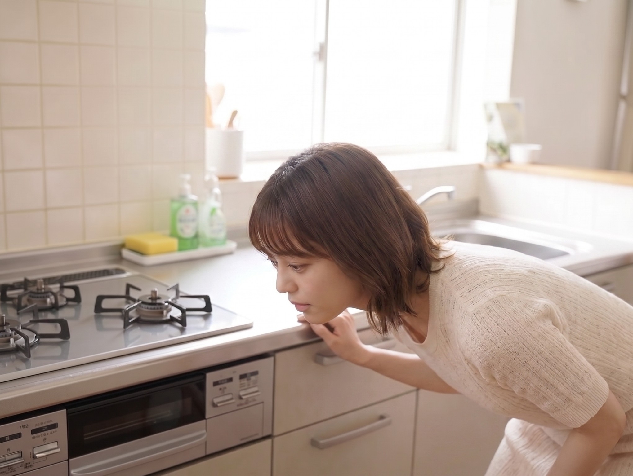 女性が魚焼きグリルの火が付かずに覗き込んでいる